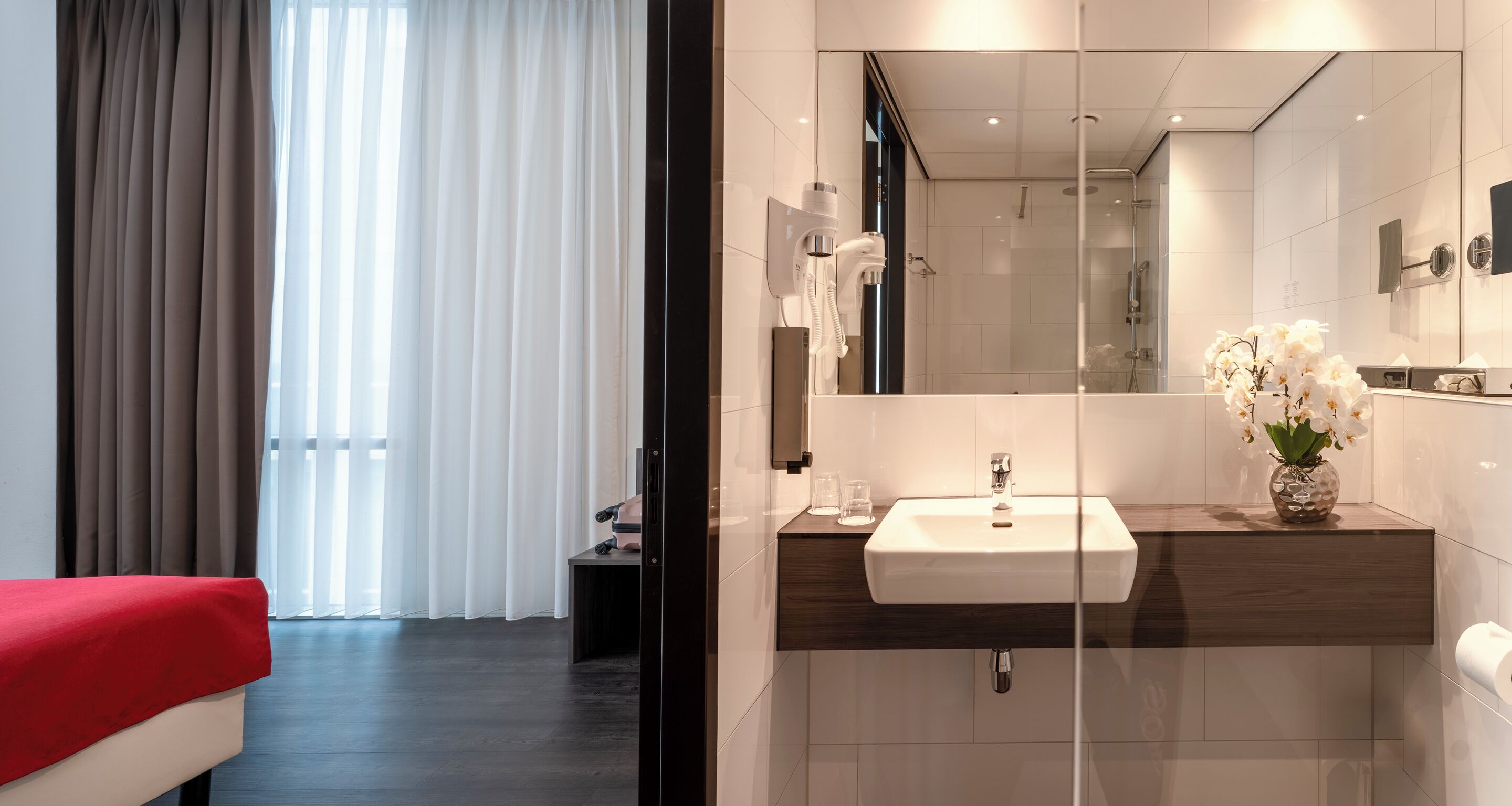 A modern bathroom with a large mirror, a sink, and a shower.