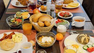Un buffet de petit-déjeuner proposant divers plats, notamment des œufs, du bacon, des toasts et des fruits.