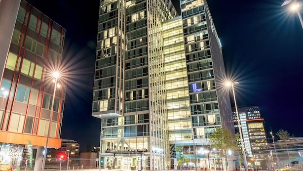 A modern high-rise building with multiple floors, large windows, and a well-lit facade. - PLAZA Premium Almere (Almere)