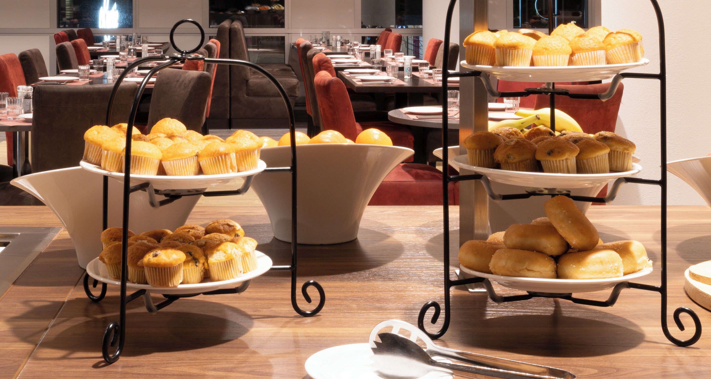 A buffet table with multiple trays of muffins and pastries.