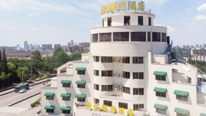 A multi-story hotel with a white facade and green awnings. - Mengpei Business Hotel (Shaoxing)