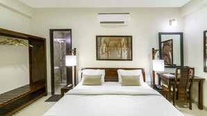 A hotel room with a large bed, a wooden wardrobe, a desk with a chair, a mirror, and a painting on the wall. - Zade House Jaipur (Jaipur)