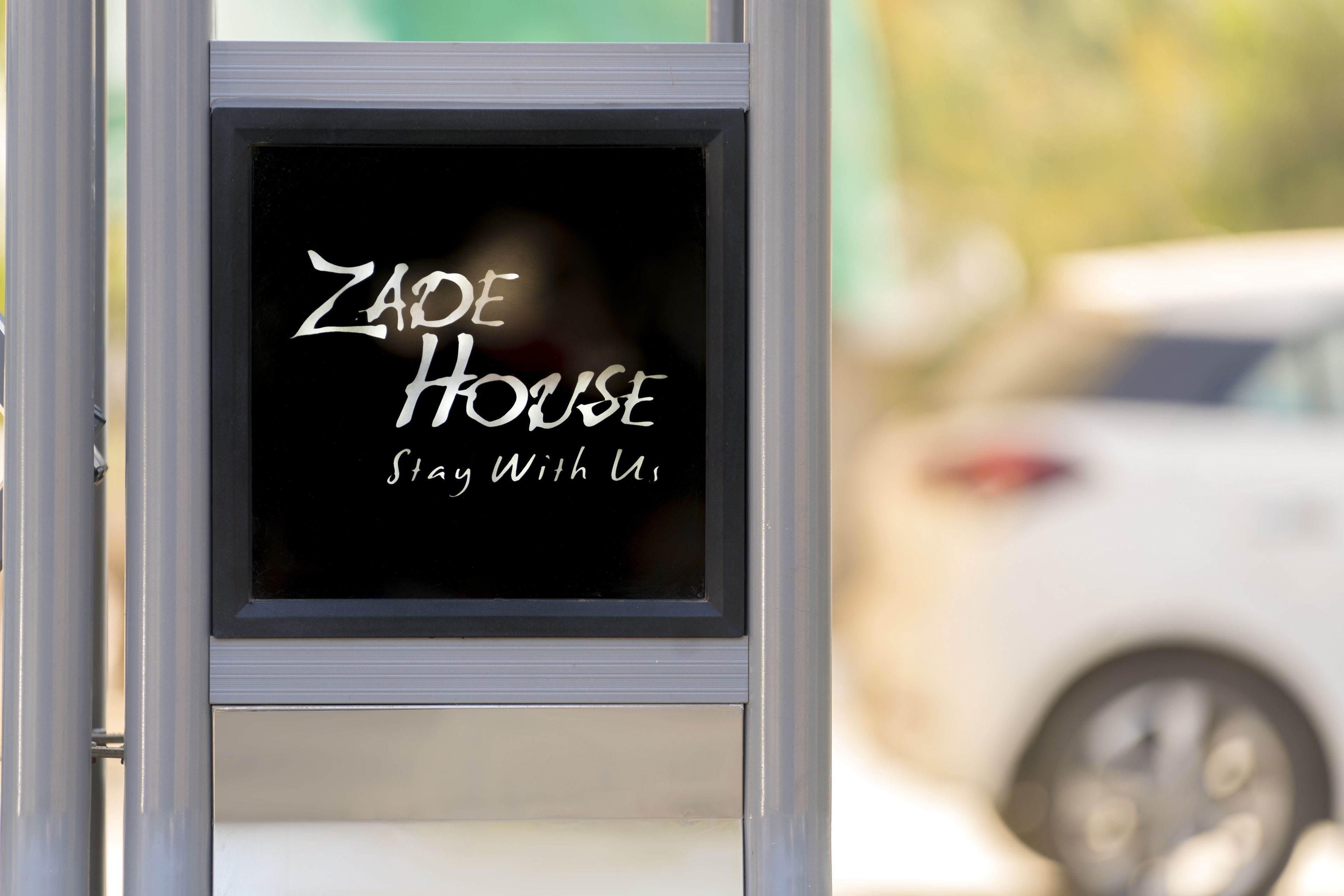 Een bordje voor 'Zade House' met de tekst 'Verblijf bij ons'.