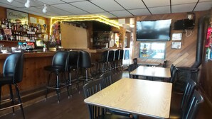 A restaurant interior with a bar area, wooden tables, and black chairs. - Tyee Restaurant and Hotel (Coupeville)