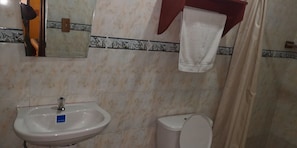Un baño con lavamanos, inodoro y una toalla colgada en un perchero.