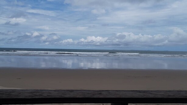 Una playa con mar tranquilo y cielo nublado.