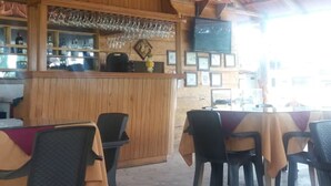 Un restaurante al aire libre con barra de madera, mesas y sillas.