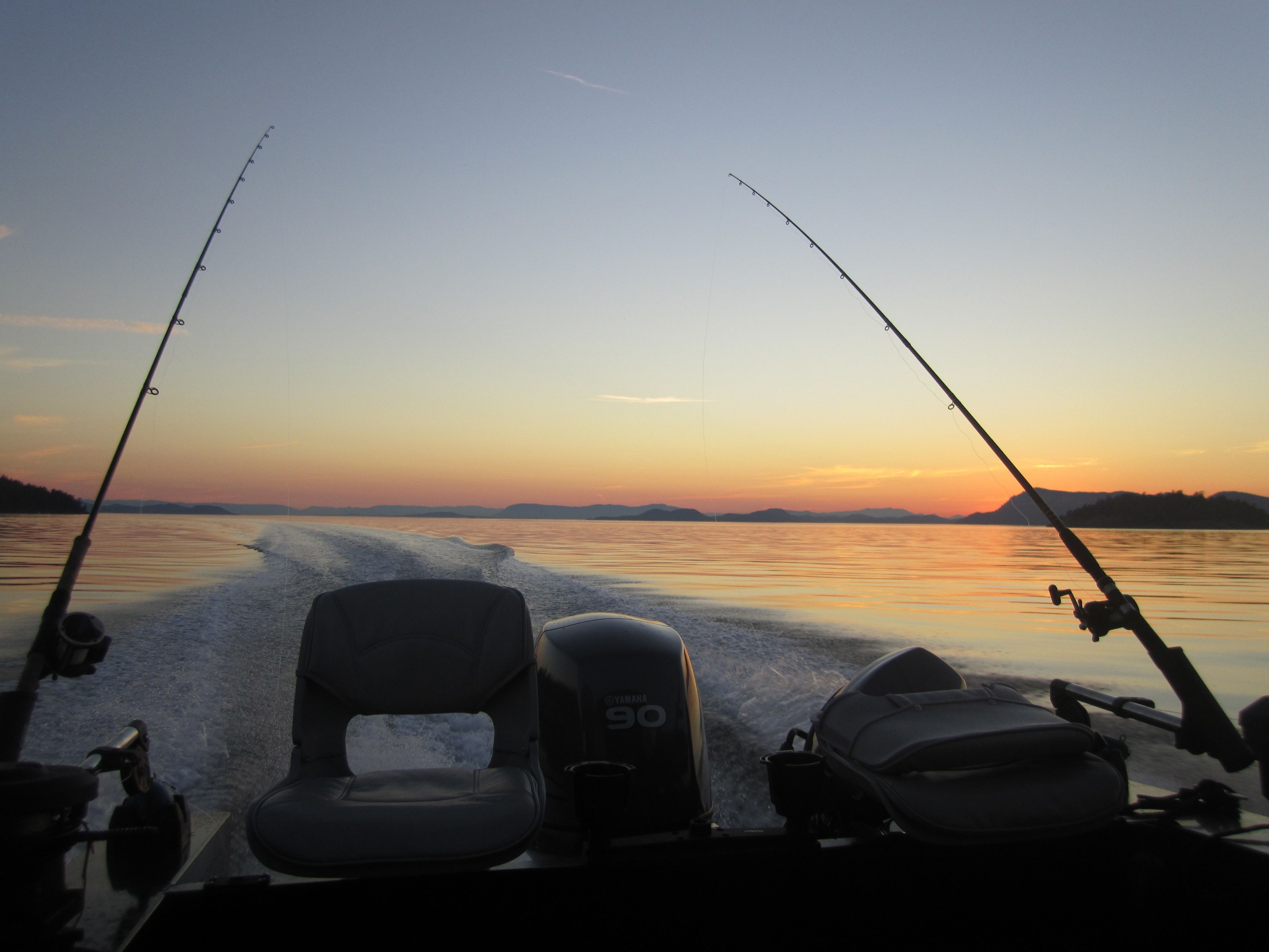 A boat with two fishing rods, a Yamaha outboard motor, and a wakeboard.