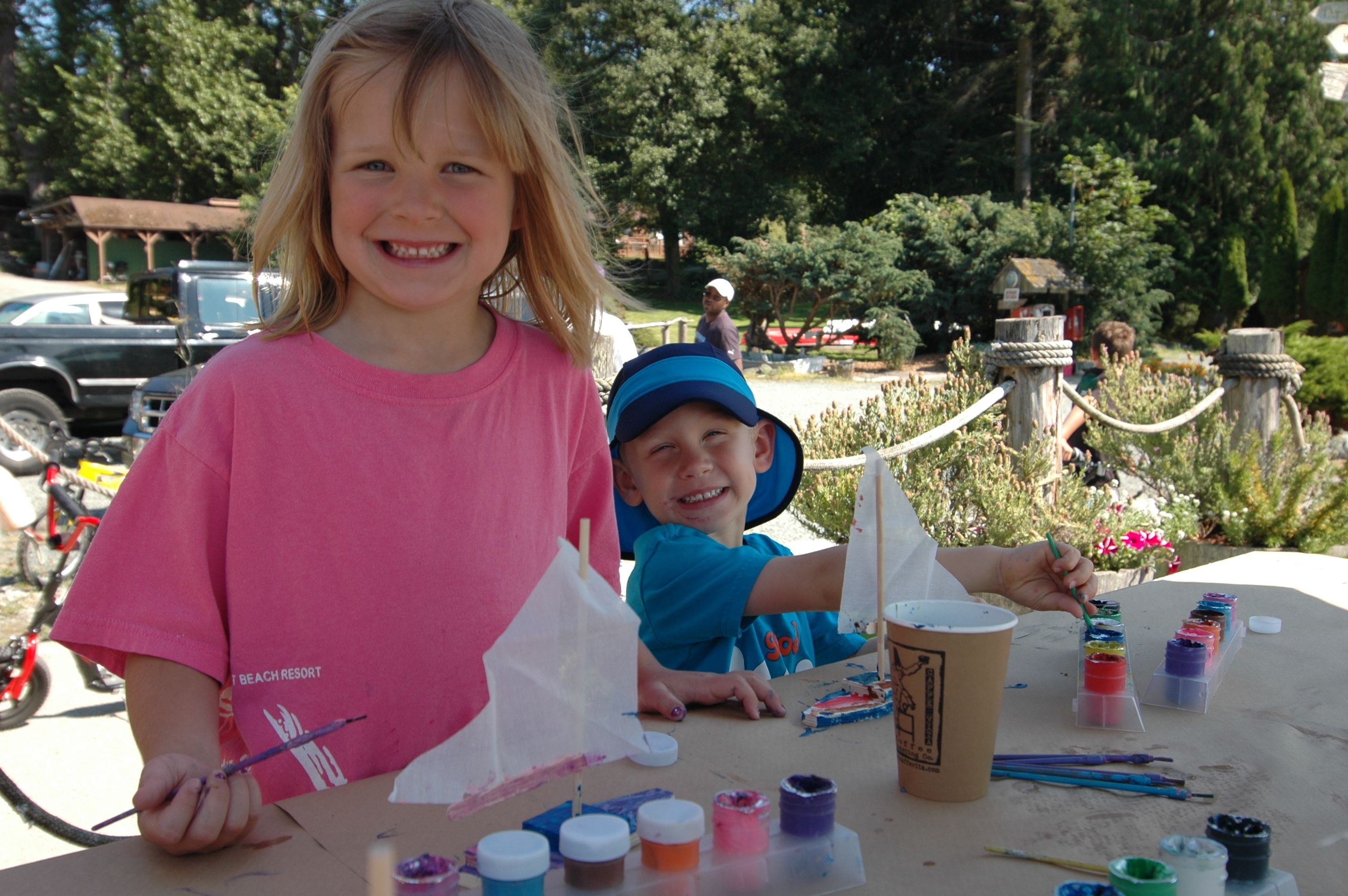 Two children painting at a table with art supplies.