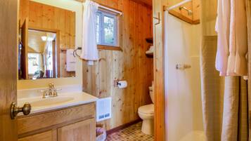 Un bagno in una cabina di legno con lavandino, WC e doccia.