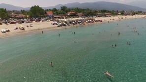 Una playa con agua cristalina, sombrillas y gente nadando.