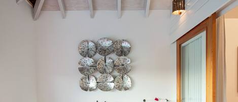 Um banheiro moderno com uma banheira independente, um objeto decorativo na parede e teto de madeira.