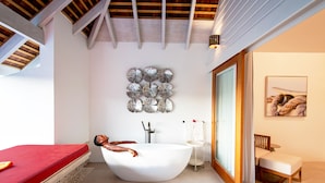 A modern bathroom with a freestanding bathtub, a wooden ceiling, and a wall-mounted decorative piece. - Escape at Nonsuch Bay Antigua - All Inclusive - Adults Only (Freetown)