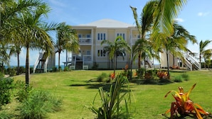 A multi-story hotel with a flat roof, surrounded by palm trees and tropical plants.
