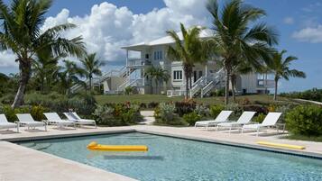 A pool area with lounge chairs, a yellow float, and a two-story building with a balcony.