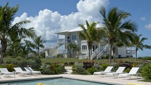 A pool area with lounge chairs, a yellow float, and a two-story building with a balcony in the background. - Buttonwood Reserve 1D (James Cistern)
