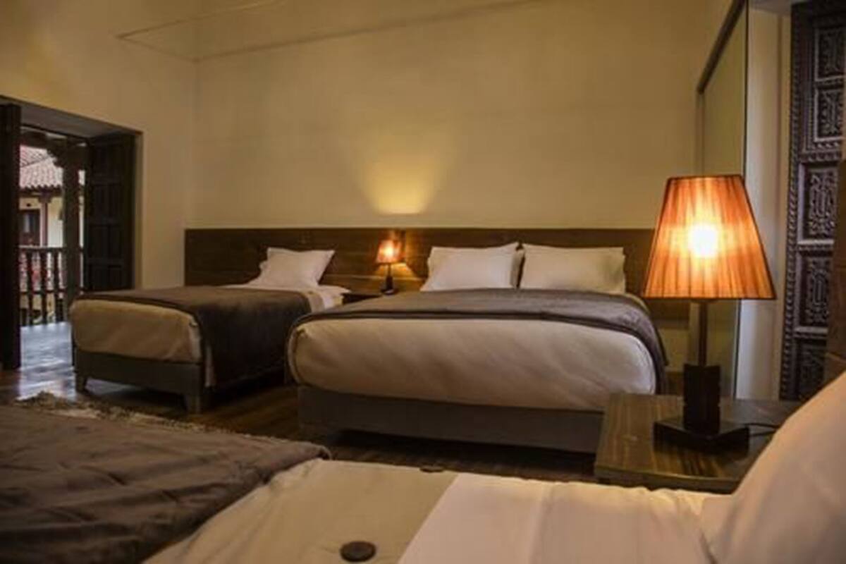 Une chambre d’hôtel avec deux lits, une table de chevet avec une lampe et une vue sur un bâtiment traditionnel situé à l’extérieur.