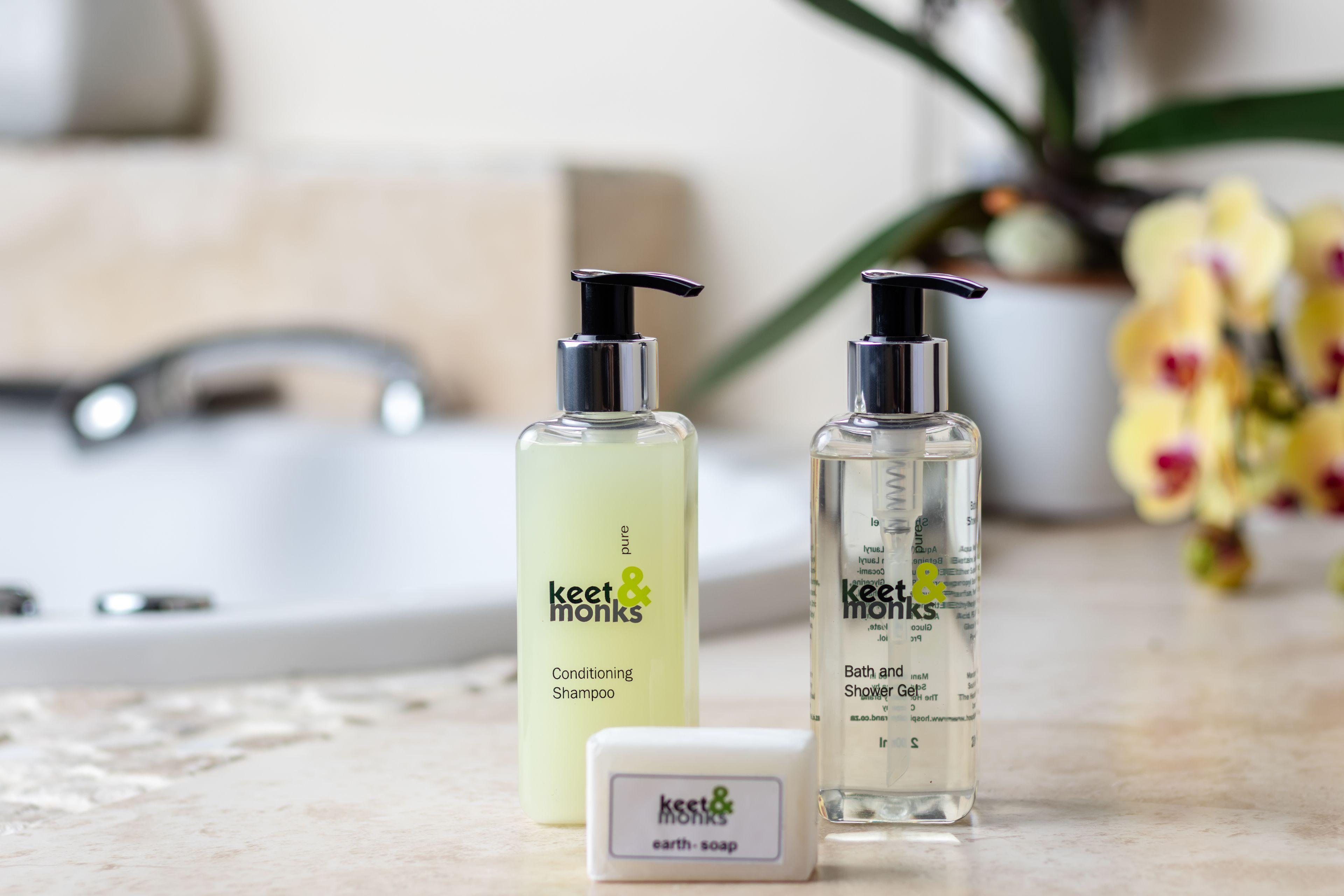 Two bottles of Keet & Monks shampoo and conditioner on a bathroom counter.