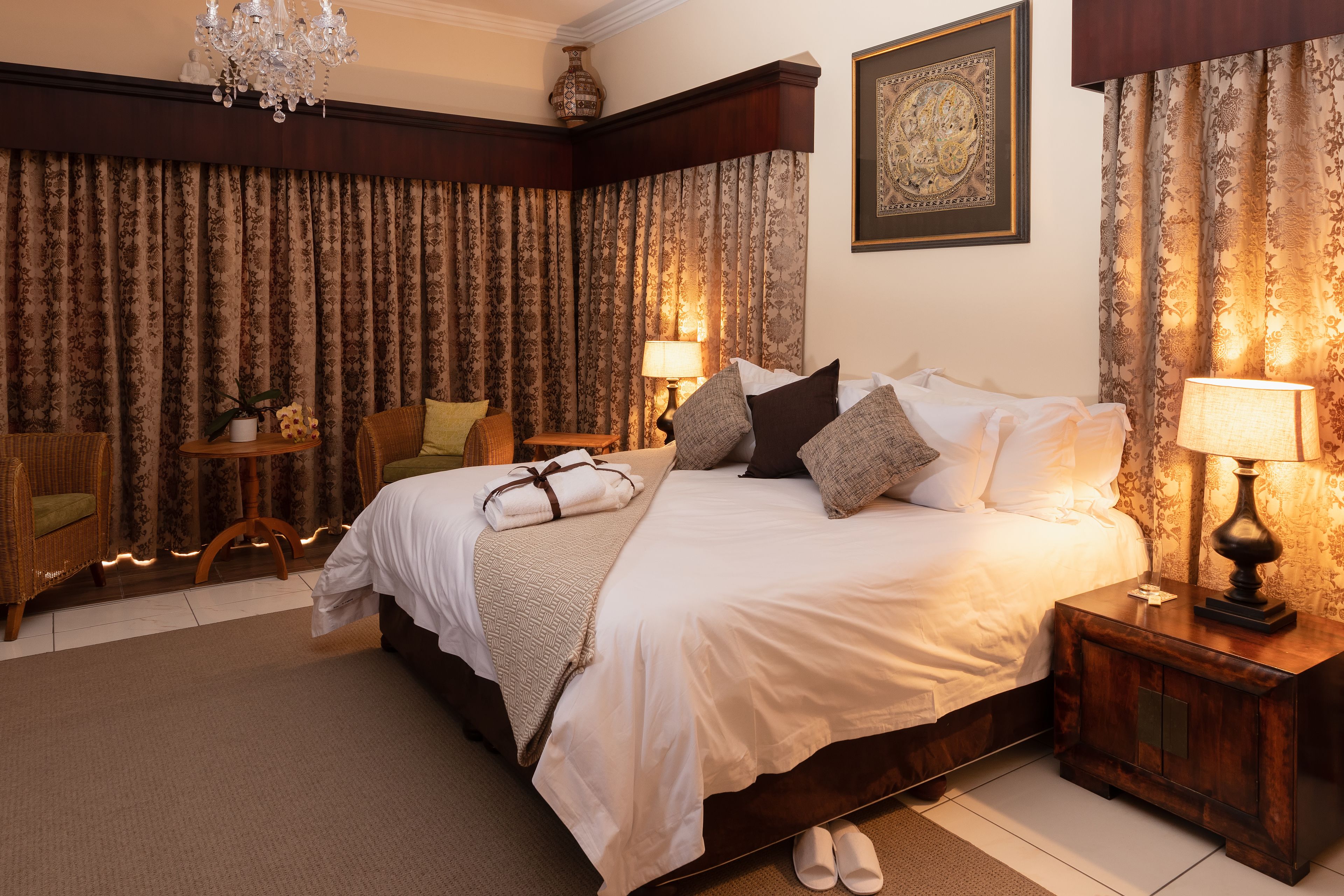 Een stijlvol ingerichte slaapkamer met een groot bed, een nachtkastje, een stoel en een tafel met een lamp.