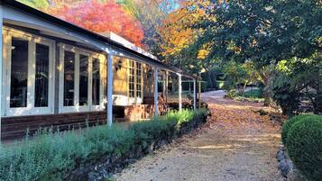 A covered walkway with a gravel path leading to a building with large windows and a wooden deck.