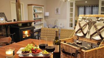 A cozy dining area with a wooden table set for a meal, a wine bottle, and a basket of cutlery.