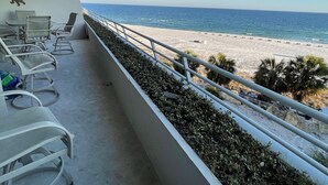 A balcony with chairs overlooking a beach.