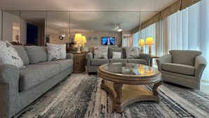 A modern living room with a grey sofa, a round coffee table, and a ceiling fan.