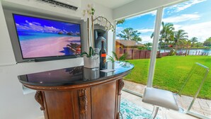 A bar area with a TV screen, a bottle of wine, and a glass.
