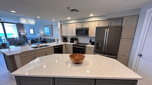 A modern kitchen with a large island, built-in appliances, and a view to the living area. - Eden West 905 Completely updated Gulf Front Condo with Stunning Views! (Pensacola)