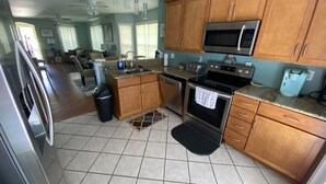 A kitchen with wooden cabinets, a stainless steel refrigerator, a microwave, an oven, and a coffee maker.