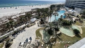 Een resort met een strand, een zwembad en een groot gebouw.