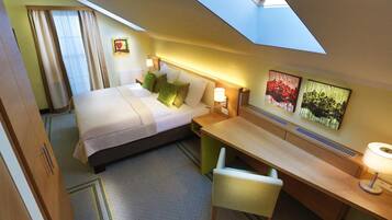 Une chambre d’hôtel avec un lit, un bureau, une chaise et des œuvres d’art accrochées aux murs.