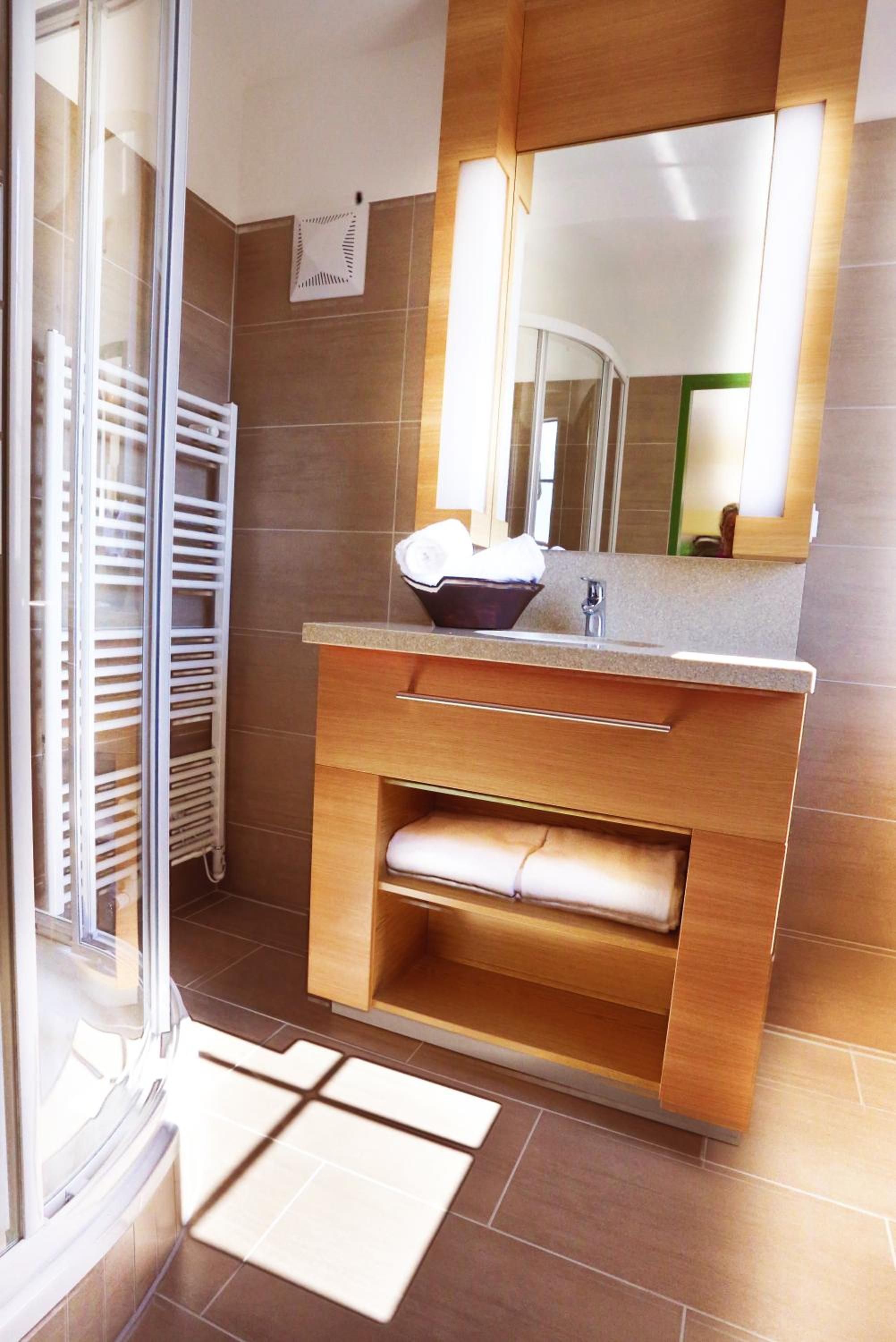 Une salle de bain moderne avec un meuble-lavabo en bois, un évier et un miroir.