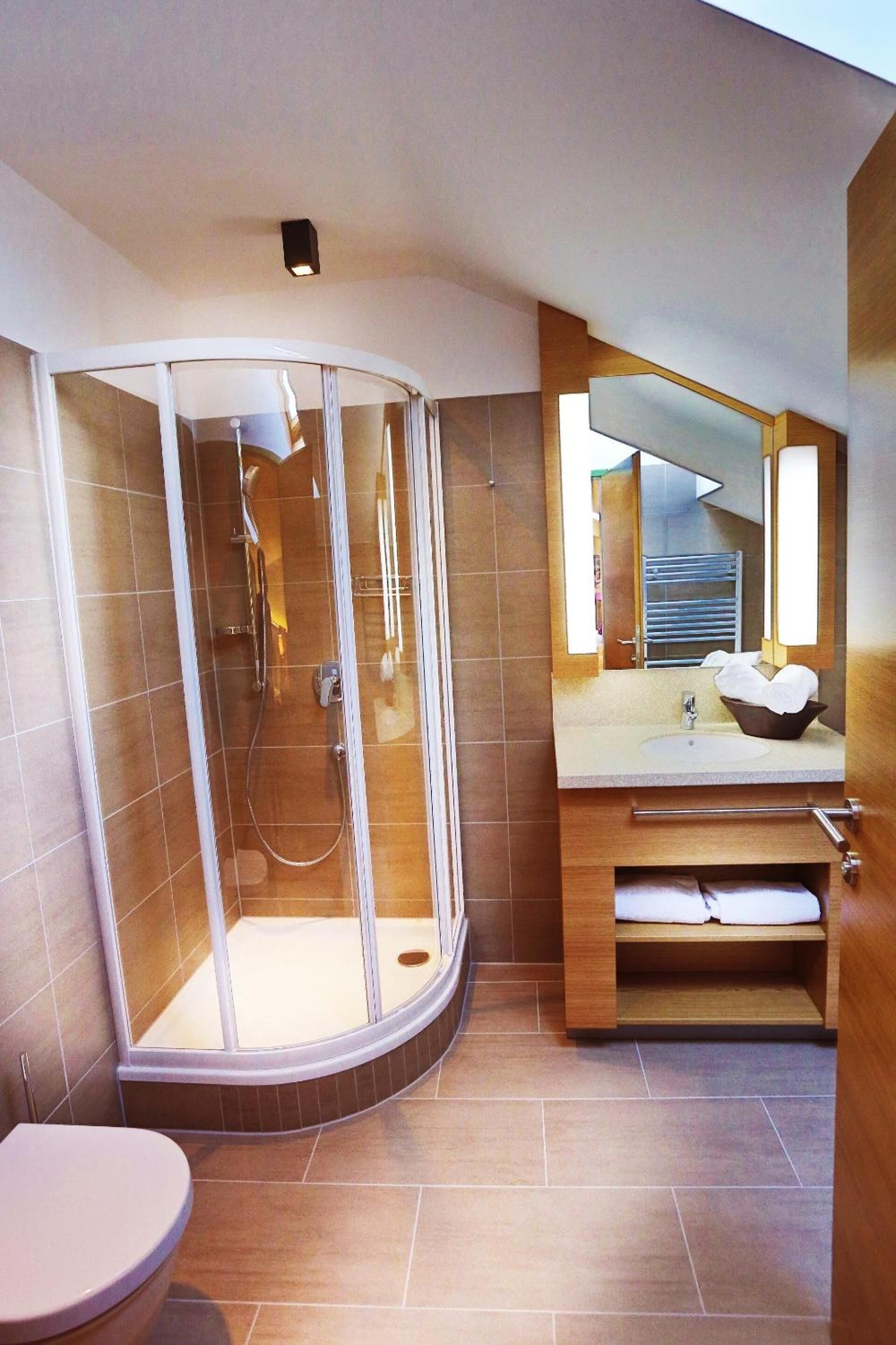 Une salle de bain moderne avec une douche à parois de verre, un meuble-lavabo en bois et des toilettes.