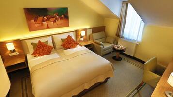 Une chambre d’hôtel avec un lit, une chaise, un bureau et un tableau au mur.