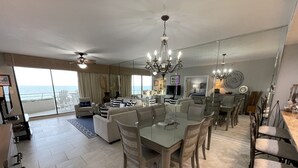 Een ruime woonkamer met een eettafel, banken en uitzicht op de oceaan.