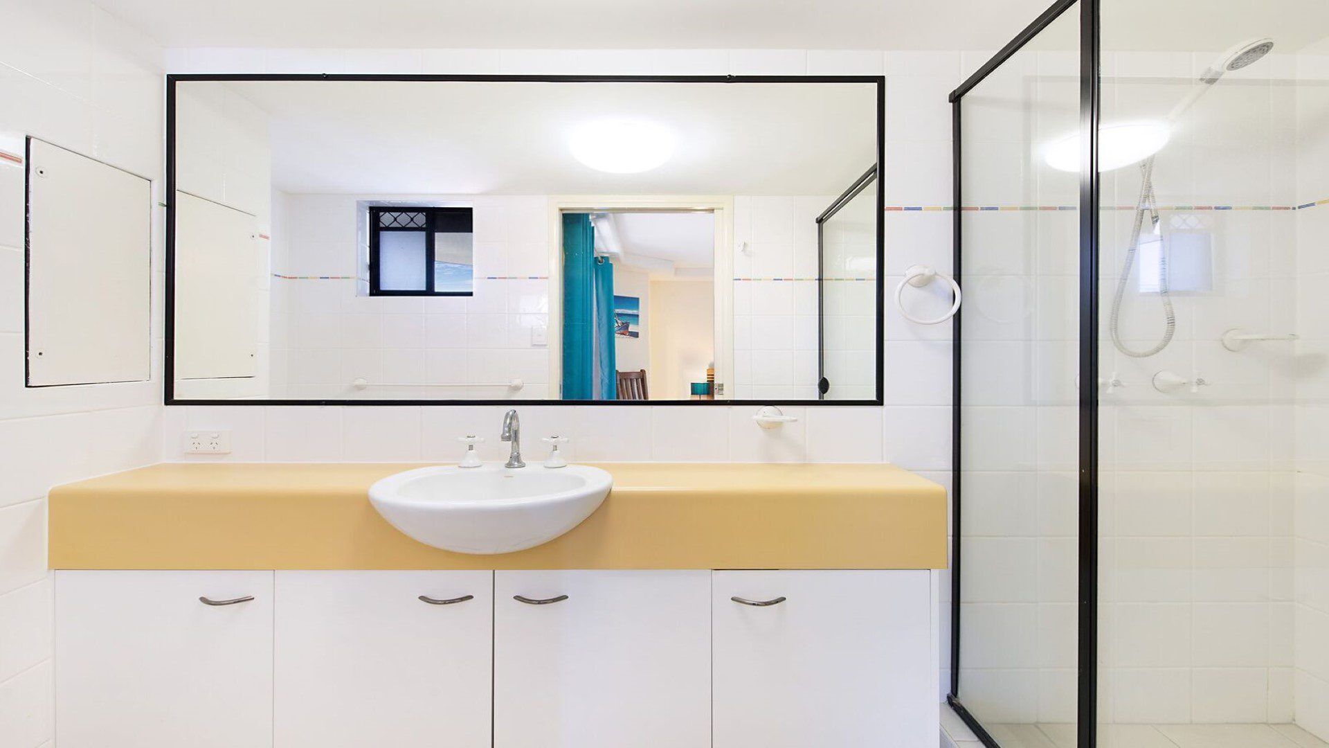 A bathroom with a white sink, a mirror, and a glass shower enclosure.