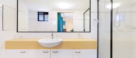 A bathroom with a white sink, a mirror, and a glass shower enclosure.
