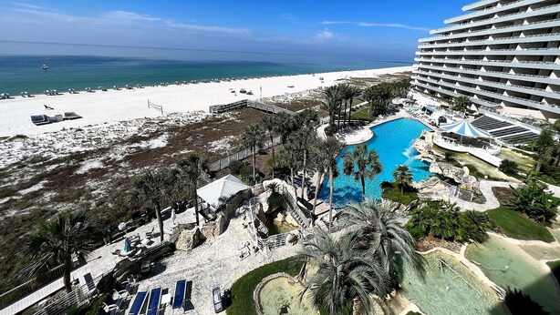 A resort with a large pool, beach, and ocean view.