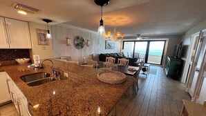 A spacious kitchen with granite countertops, a dining area with a round table, and a large window offering a view.