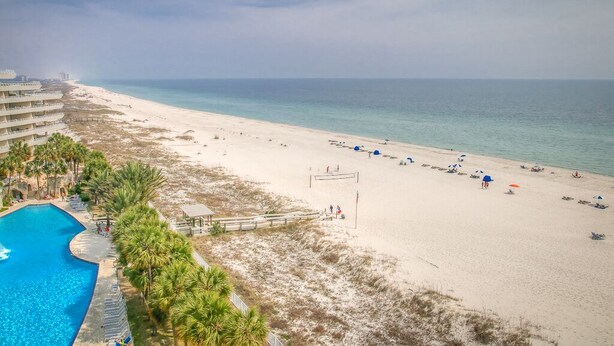 A beach resort with a swimming pool, beach chairs, and umbrellas. - Gulf Front Condo with Stunning Views! (Pensacola)
