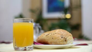 Une table avec un verre de jus d’orange et un sandwich sur une assiette.