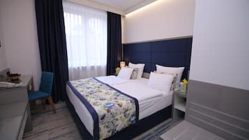 Une chambre d’hôtel avec un grand lit, un bureau, une chaise et une table de chevet avec une lampe.