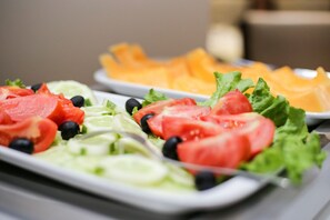 A buffet with various food items including sliced tomatoes, cucumbers, lettuce, and black olives. - Old Town (Sarajevo)