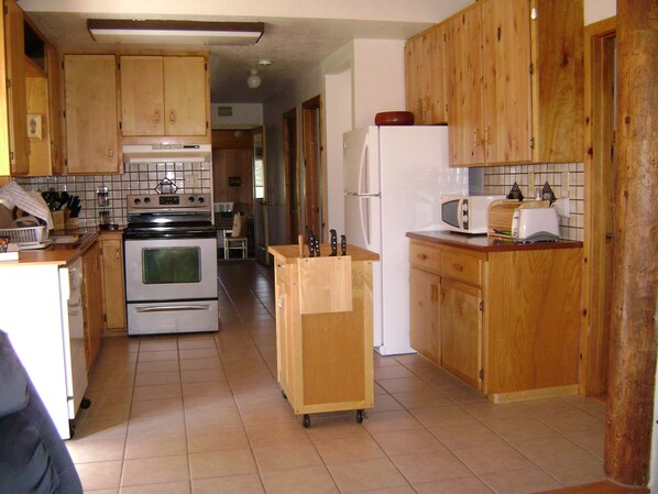 A kitchen with wooden cabinets, a stove, a refrigerator, and a microwave.