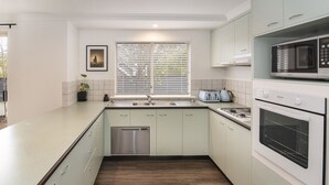 A modern kitchen with light green cabinets, a stainless steel dishwasher, a microwave, and a toaster. - @WineNwaves Margaret River (Margaret River)