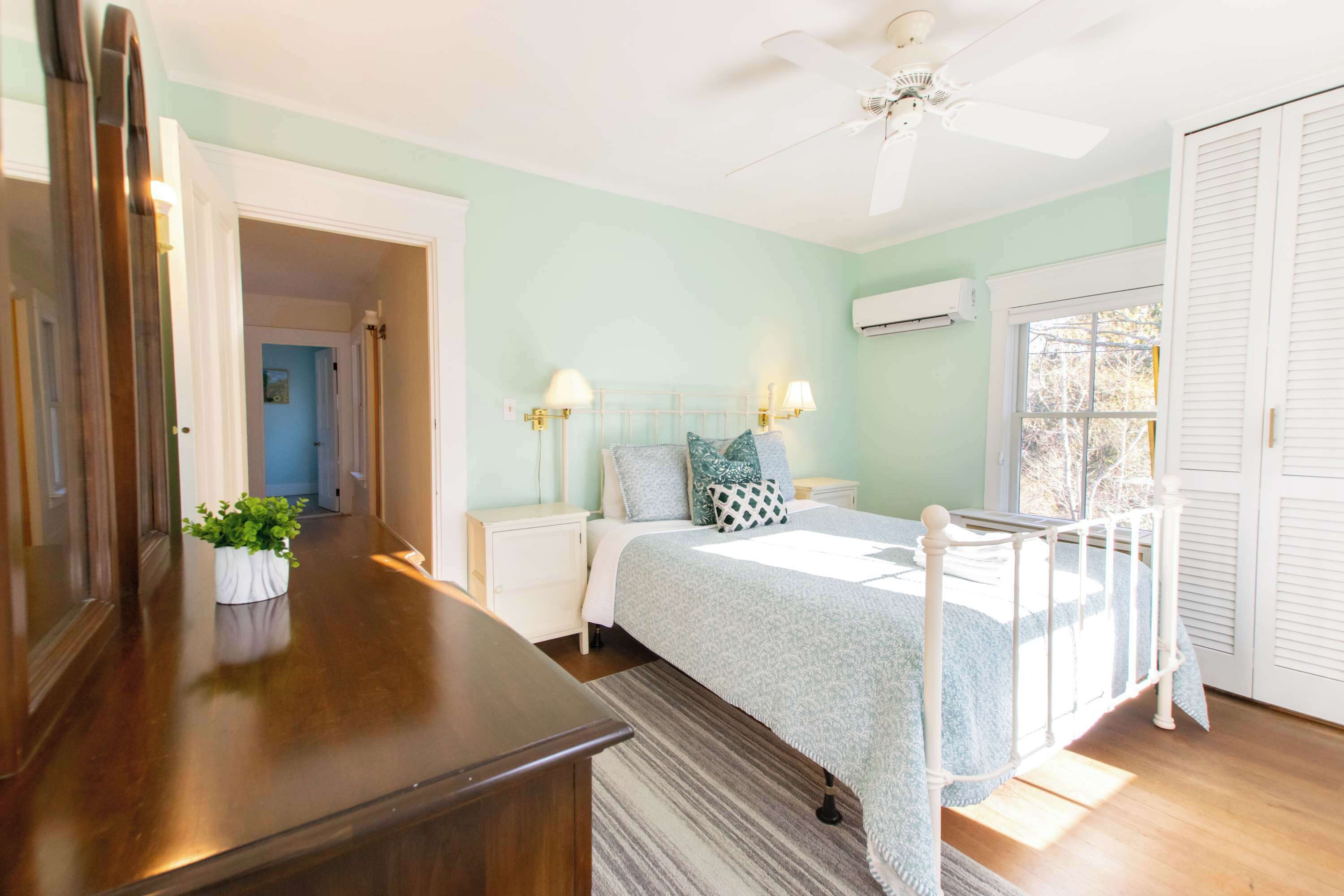 Une chambre à coucher avec un lit, des tables de chevet, un ventilateur de plafond et une fenêtre.