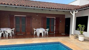 A swimming pool with a tiled edge, surrounded by a patio area with two tables and chairs. - 4 suites, air conditioning, TV, internet, swimming pool, 150 meters from the beach! Pets allowed! (Guarujá)