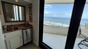 Una cocina con lavaplatos, lavavajillas y un amplio ventanal con vista al océano.