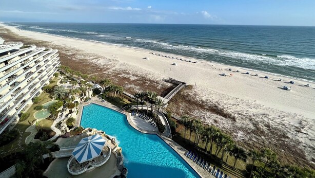Un resort con una piscina grande, acceso a la playa y vistas al océano.